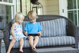 Caucasian children using digital tablet on sofa