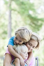 Caucasian mother hugging children outdoors