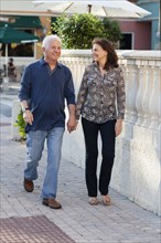 Older Caucasian couple holding hands on sidewalk