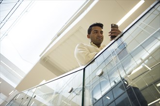 Asian businessman texting with cell phone on office staircase