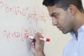 Asian businessman writing formula on whiteboard