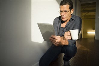 Hispanic businessman using digital tablet in office hallway