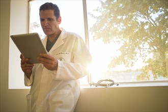 Hispanic doctor reading medical chart at window