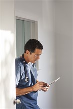 Hispanic doctor using digital tablet in hallway