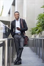 Black businessman using cell phone outside building