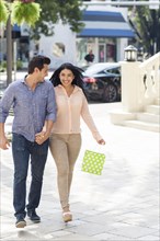 Hispanic couple walking on city sidewalk