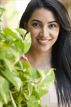 Hispanic woman smiling behind plant