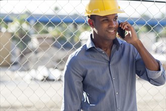 Black architect in hard hat talking on cell phone