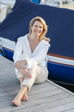 Caucasian woman sitting on deck in harbor