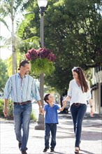 Caucasian mother and father walking with son on sidewalk