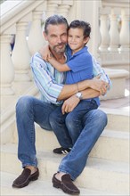 Caucasian father and son hugging on front stoop