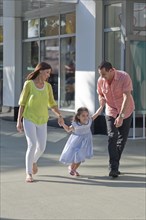 Hispanic family holding hands on sidewalk