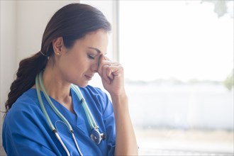 Frustrated Mixed race nurse at window