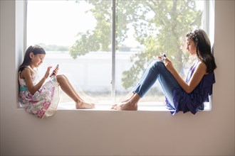 Sisters using technology in window