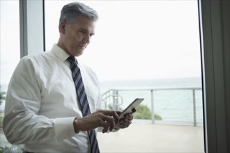 Caucasian businessman using digital tablet at window