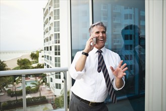 Caucasian businessman talking on cell phone on balcony