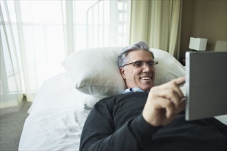 Caucasian man using digital tablet in bed