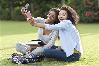 Black women taking selfies in park
