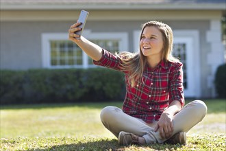 Caucasian girl taking selfie in backyard