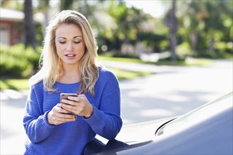 Caucasian woman using cell phone outside car