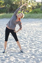 Caucasian woman stretching on beach