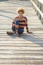 Black woman sitting on wooden boardwalk