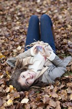 Hispanic girl laying in autumn leaves