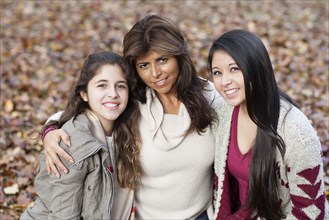 Hispanic mother and daughters hugging outdoors