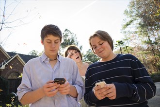 Frustrated Caucasian mother watching sons use cell phones