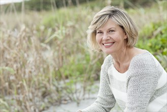 Smiling Caucasian woman sitting on beach