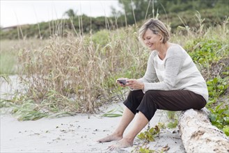 Caucasian woman using cell phone on beach