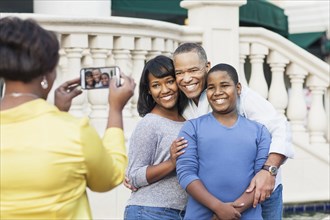African American woman taking cell phone photograph of family