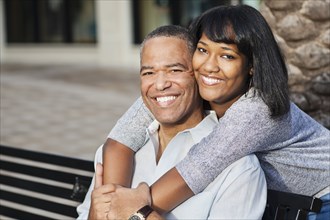 African American father and daughter hugging on bench