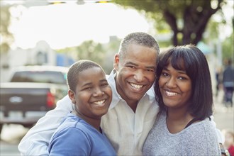 African American father and children hugging in city