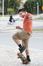 Mixed race man doing trick on skateboard