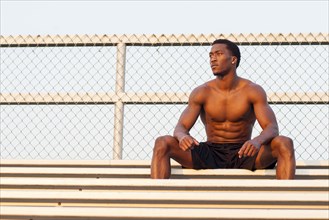 Serious Black athlete siting on bleachers