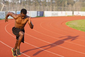 Black athlete running on track in sports field