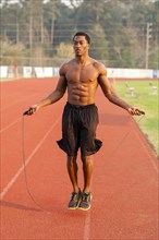 Black athlete jumping rope on track in sports field