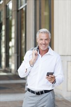 Caucasian businessman using cell phone in city
