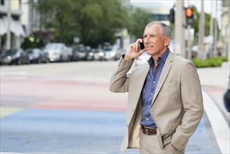 Caucasian businessman talking on cell phone at crosswalk
