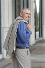 Caucasian businessman carrying jacket on city sidewalk