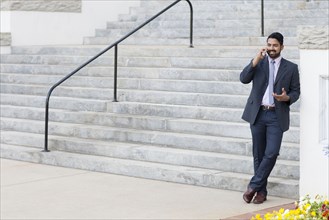 Indian businessman talking on cell phone by steps