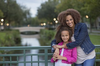 Mixed race mother and daughter hugging on bridge