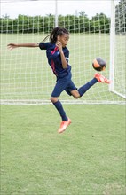 Mixed race boy kicking soccer ball on field