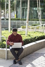 Black businessman using laptop outdoors