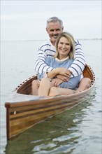 Older Caucasian couple hugging in canoe