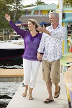 Older Caucasian couple waving from pier