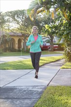 Caucasian woman jogging on sidewalk