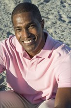 Portrait of smiling Black man sitting on beach