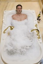 Hispanic man relaxing in bubble bath